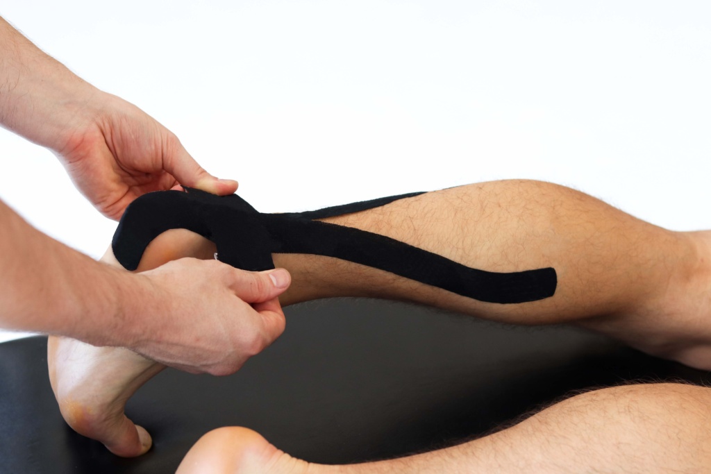 Kinesiology,taping,treatment,with,black,tape,on,male,patient,injured