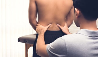 Asian,male,therapist,in,clinic,giving,massage,on,lower,back