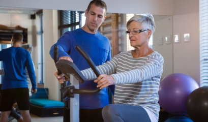 woman on exercise bike wondering if medicare covers physiotherapy